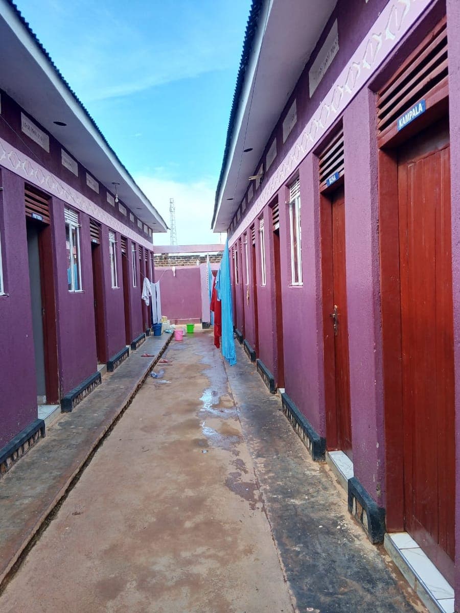 Clean row of guest rooms with named doors and a bright sky
