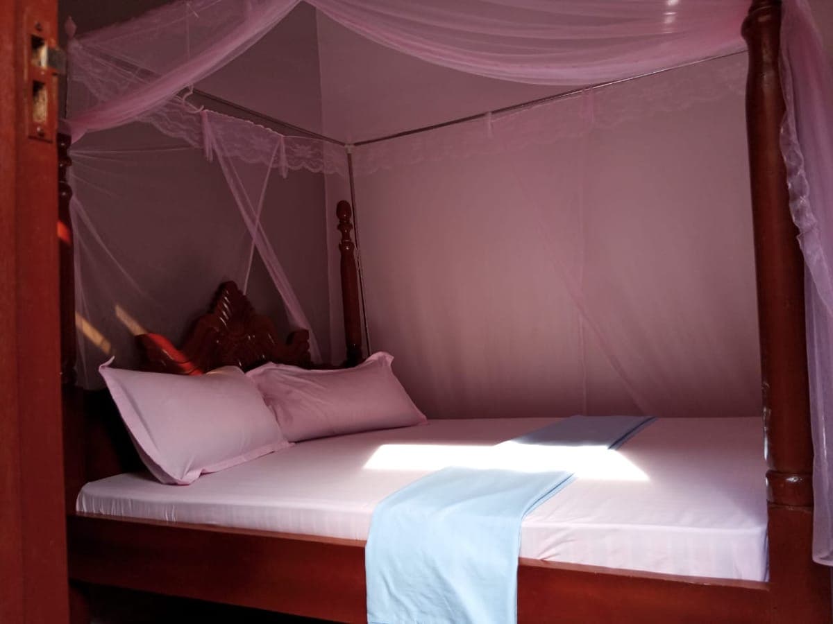 Cosy room with a four-poster bed and a soft pink canopy