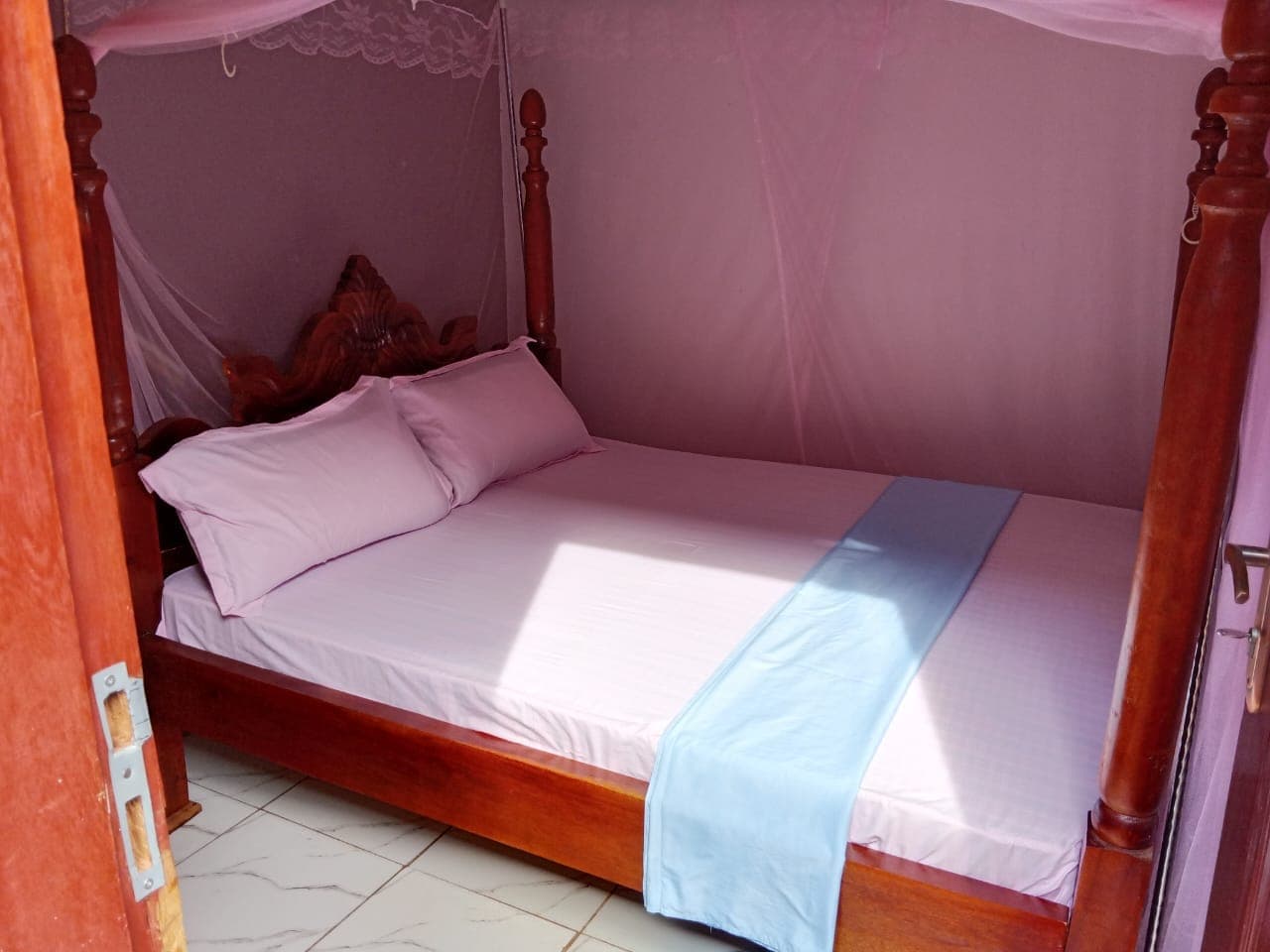 Self-contained single room with fresh pink linen and a tiled floor