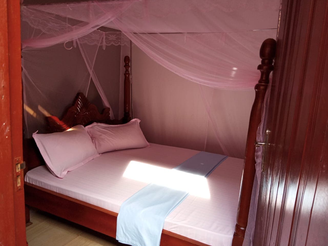 Standard single room with clean bedding and a mosquito net