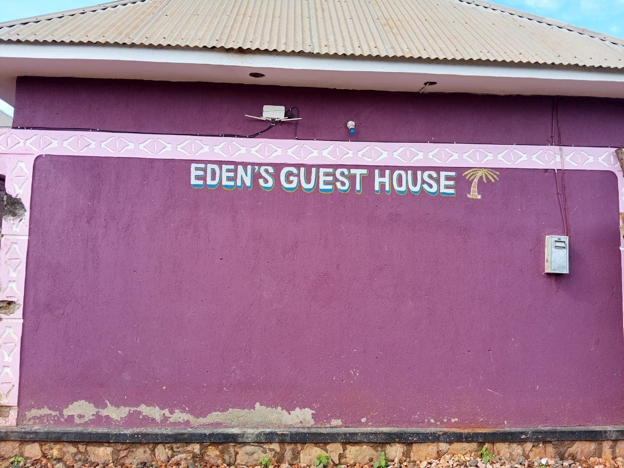 “Eden's Guest House” painted on the building wall under a clear sky